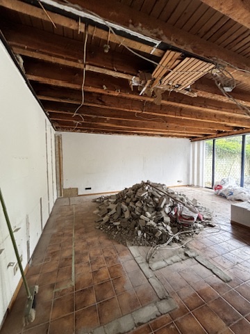 Entkernter Wohnraum mit geöffneter Decke und Rückbaumaterial