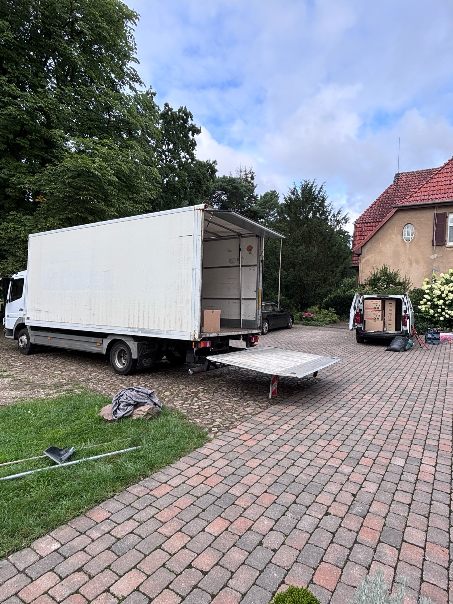 Umzugs-LKW mit Ladebordwand und Transporter vor dem Objekt